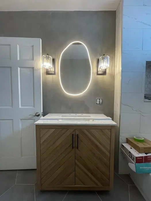 Finished bathroom with backlit LED mirror and two wall sconces over a vanity