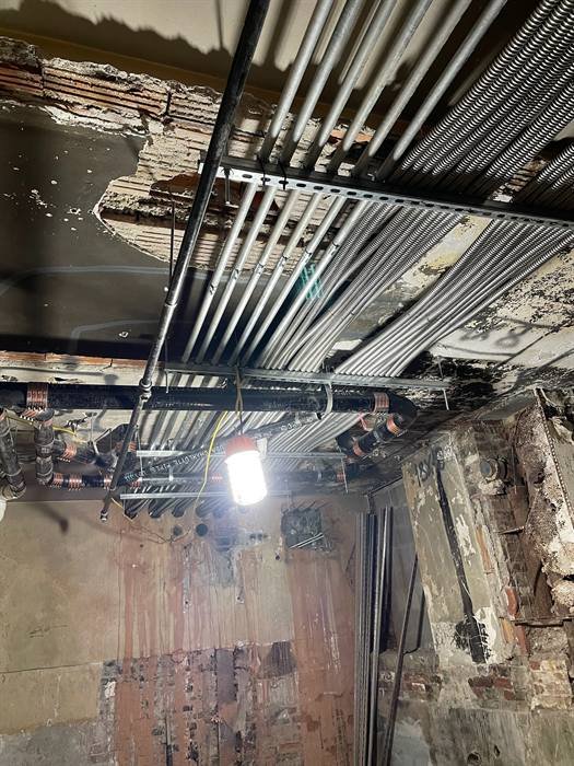 Overhead electrical conduit routed through a commercial ceiling structure