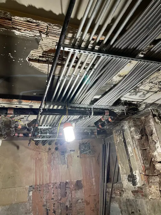 Overhead electrical conduit routed through a commercial ceiling structure