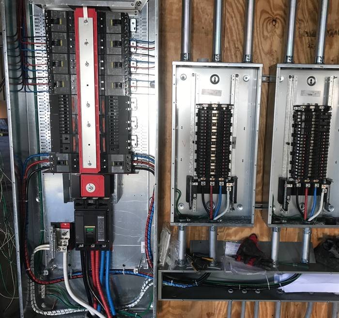 Multiple electrical panels installed and wired on a plywood backboard