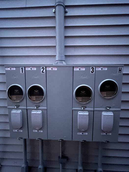 Exterior electrical meter sockets installed and numbered on a building wall