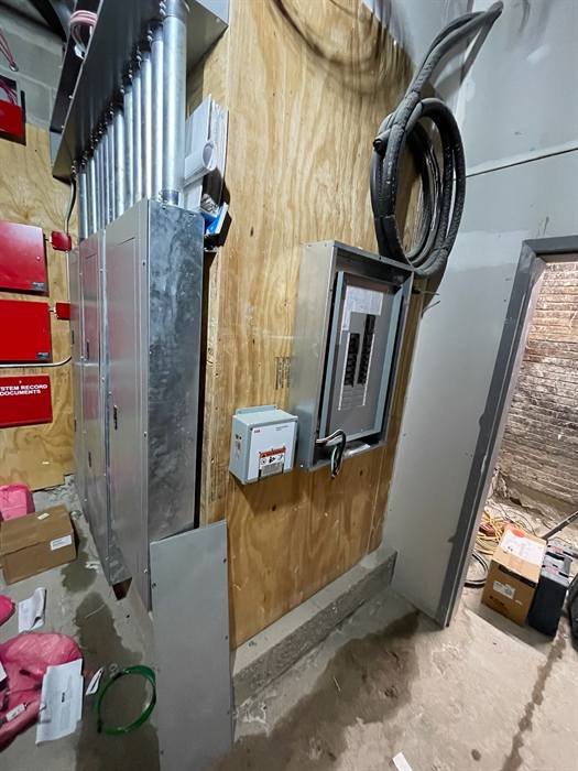 Fire alarm system equipment installed alongside electrical panels and conduit
