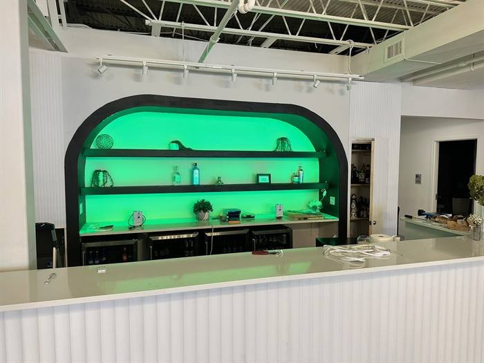 Green LED accent lighting installed behind a commercial bar and display shelving