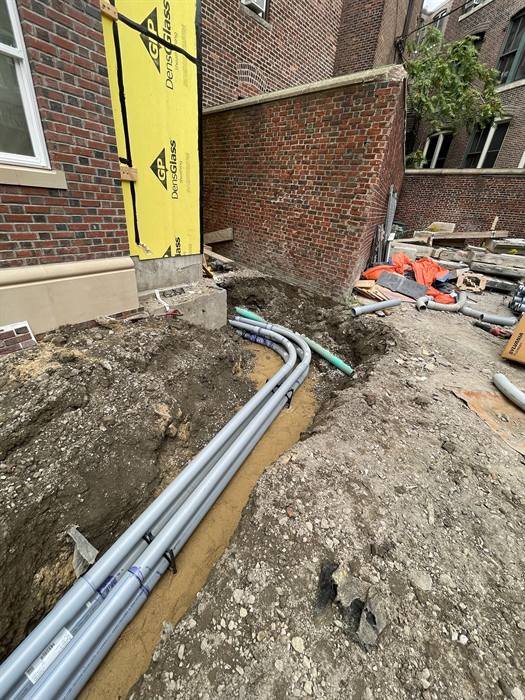 Underground electrical conduit installed in a trench along a building foundation